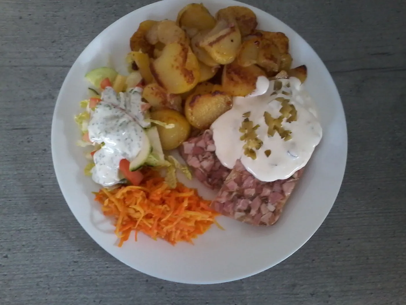 Hausgemachte Sülze mit Remoulade, Bratkartoffeln und Salat.
