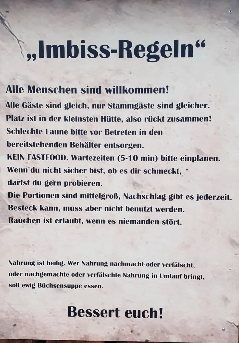 Emailleschild mit den „Imbiss-Regeln“ des Refektoriums, u. a. „KEIN FASTFOOD“ und „Nahrung ist heilig“.