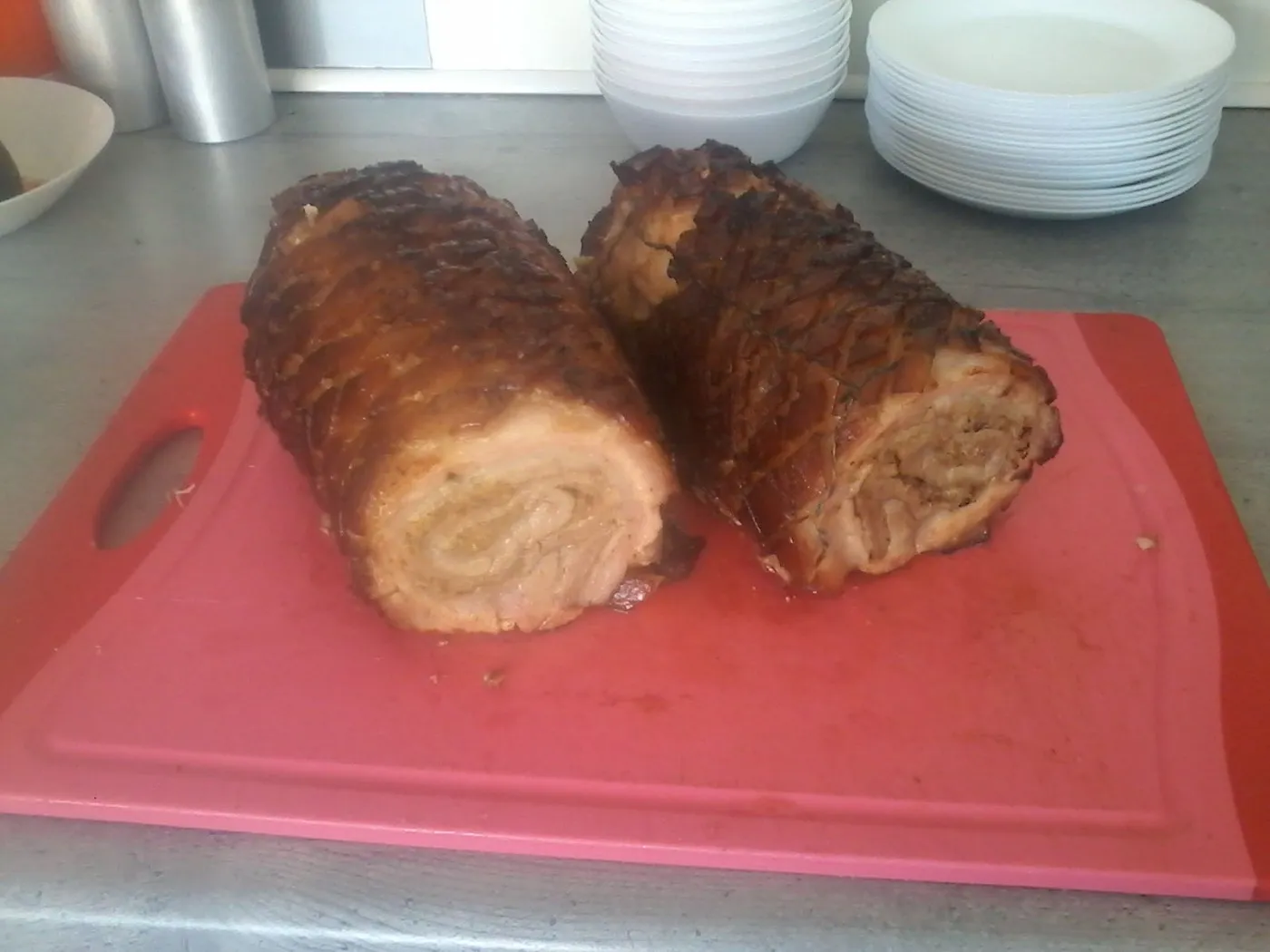 Frisch gebratener Rollbraten mit Kruste, in zwei Hälften auf einem Schneidebrett in der Küche.